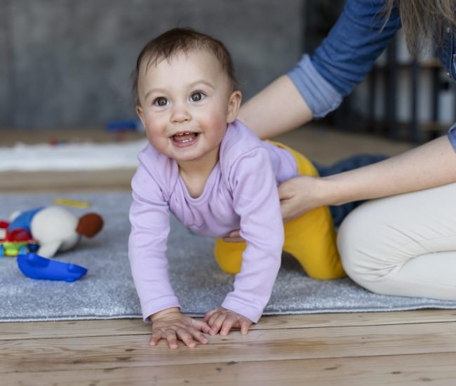 smiling-baby-crawling-being-held-by-his-mother